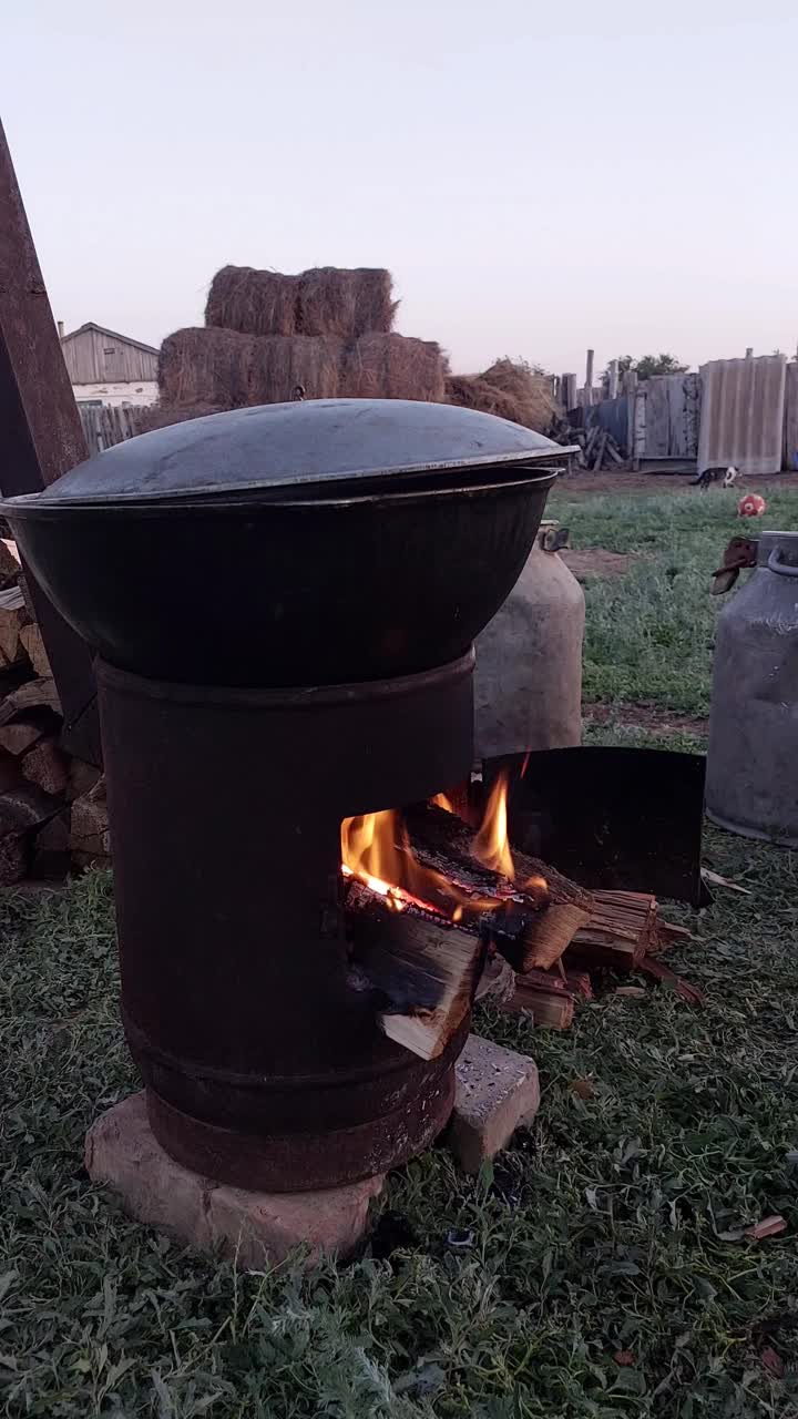 在大锅上烹饪的自制户外烤箱。用大锅在火上烹调食物。在炉子里烧柴。视频素材