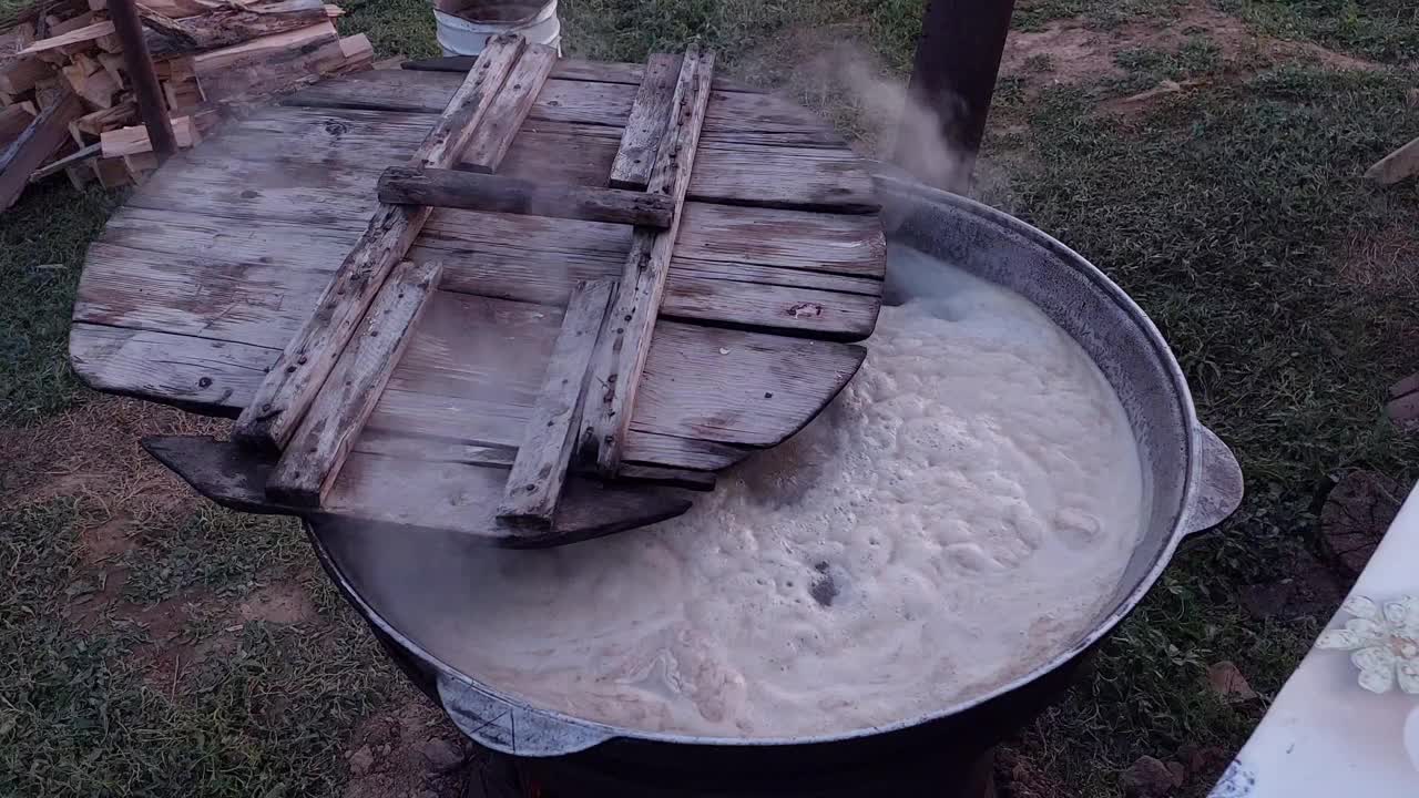 在街上用大锅煮肉。在大锅里沸腾的汤。用大锅在火上烹调食物。锅上的木盖，锅里盛着煮着的食物。在大锅里沸腾。视频素材