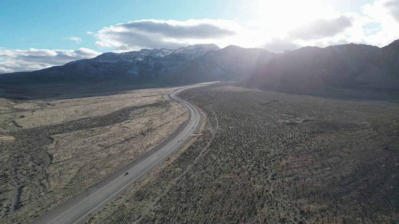 航拍视频显示，道路上的汽车被干燥的岩石高山包围视频素材