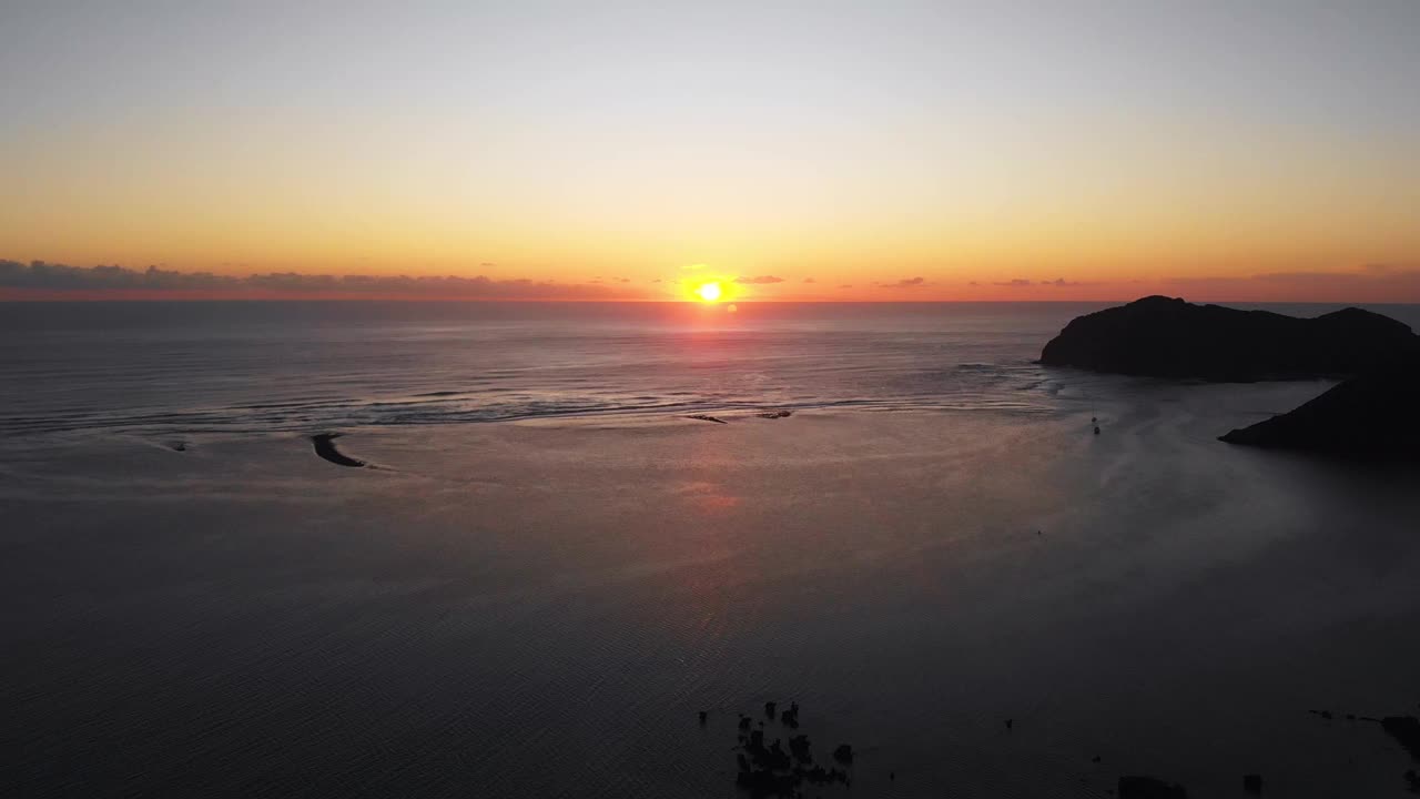 无人机拍摄的平静的海景和山的剪影在太阳落在地平线上视频素材