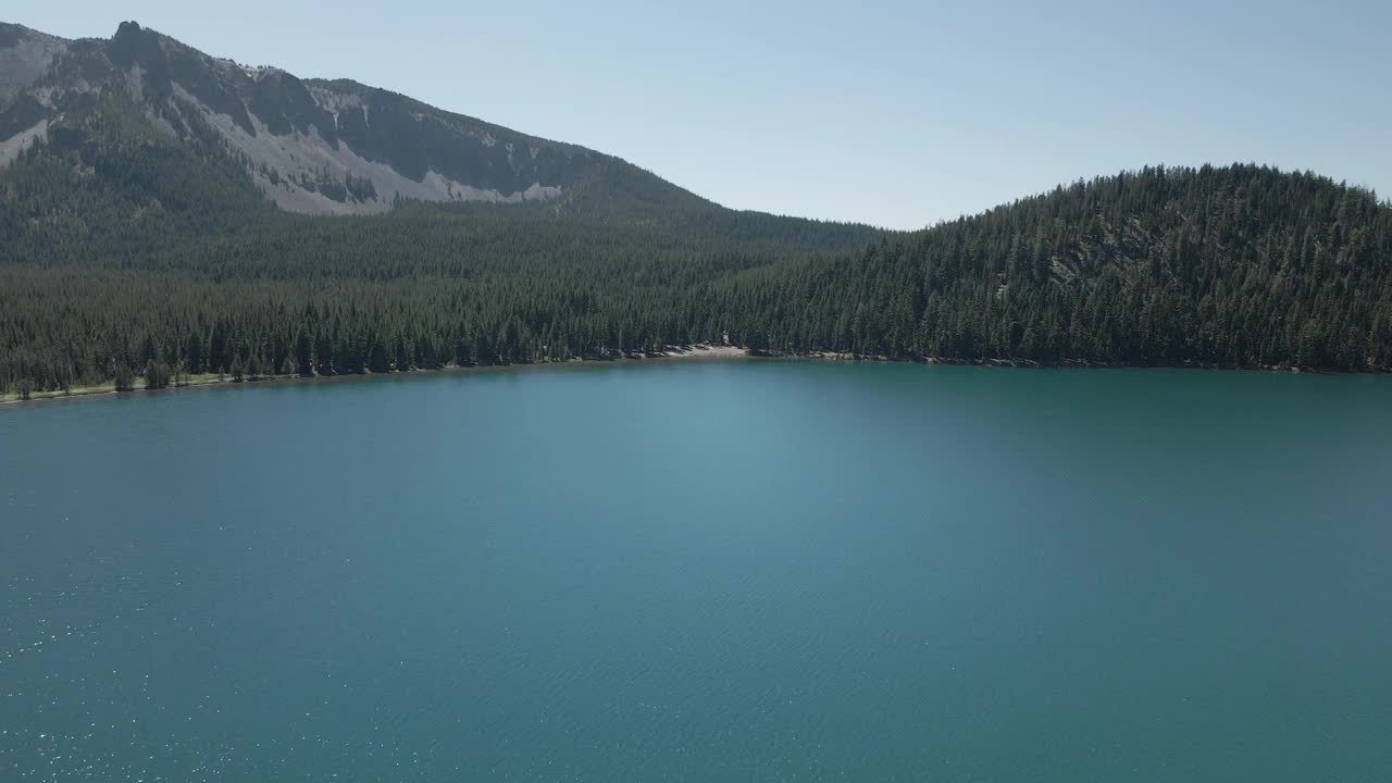 美丽的风景镜头飞过宁静的蓝色湖泊，云杉树和蓝天视频素材