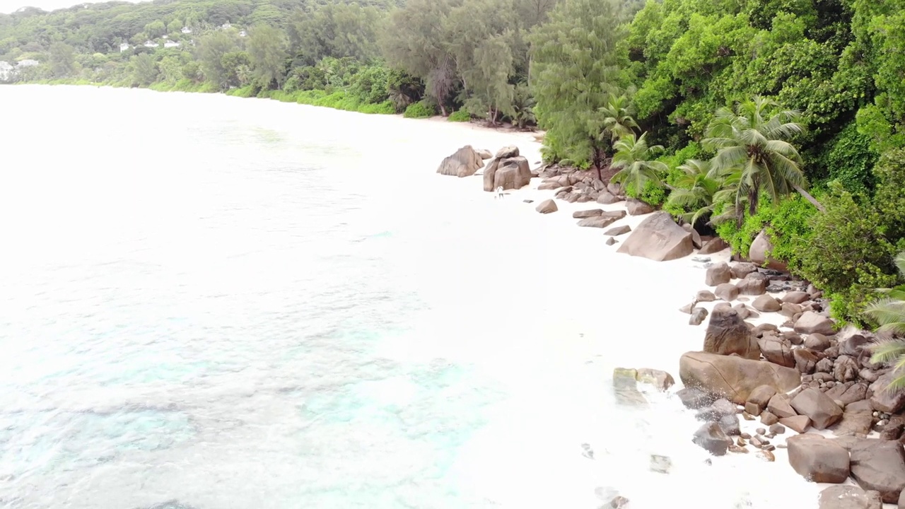 在塞舌尔的拉迪格岛海滩上，岩石海岸和绿色棕榈树的景观视频素材