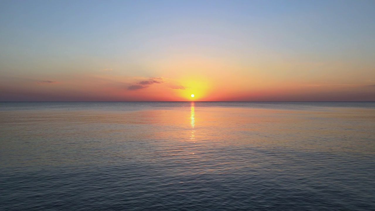 日落时宁静大海的鸟瞰图。场景有广阔的水空间，地平线和夜空视频素材