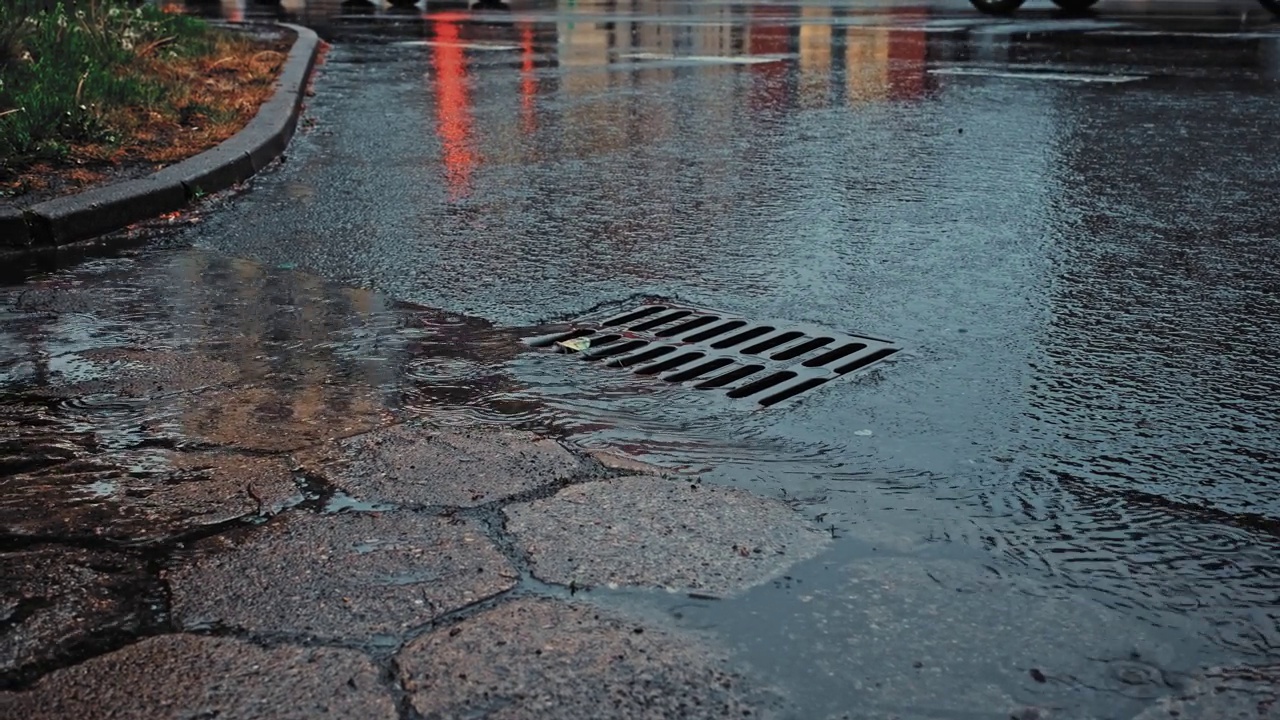 雨水顺着街道雨水下水道排水口流下视频素材