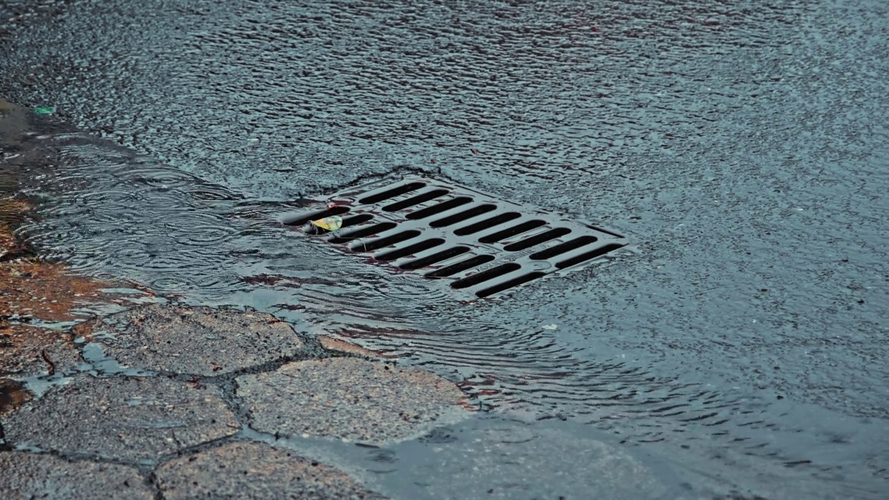 雨水顺着街道雨水下水道排水口流下视频素材