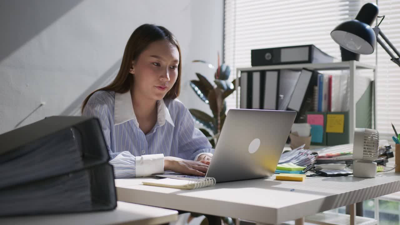 开朗的亚洲女性在办公室使用笔记本电脑视频素材