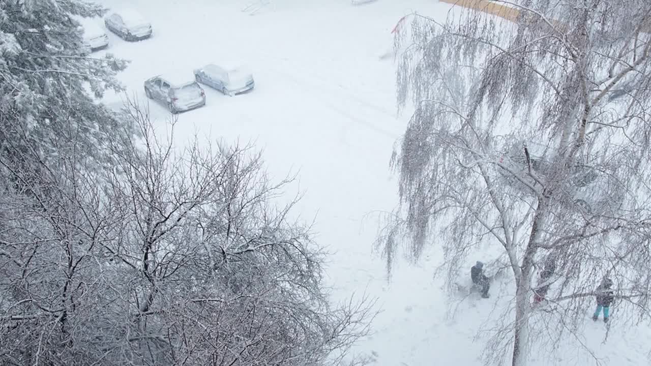 巴尔干半岛的暴风雪。城市街道和庭院出现大雪和大风。白雪覆盖的道路。巨大的白色雪花盘旋着。孩子们在雪地里玩耍视频素材