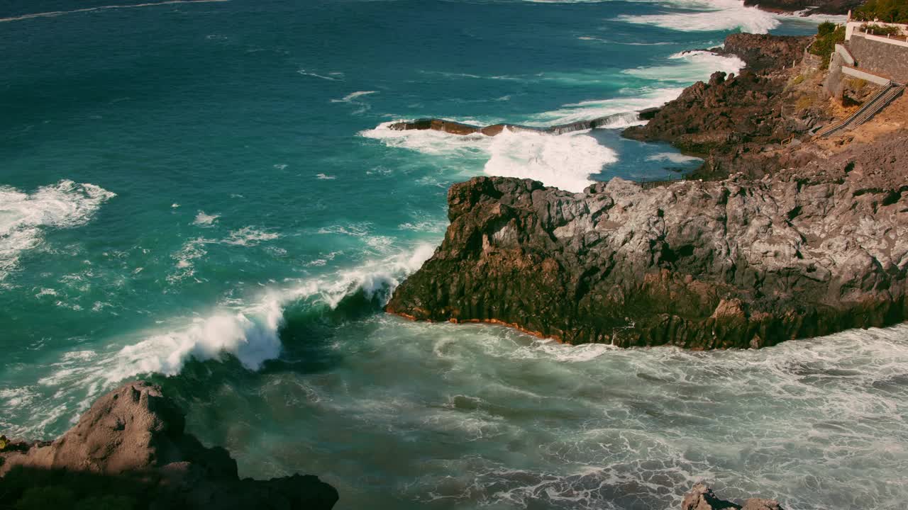 强大的海浪冲击岩石海岸，暴风雨的海洋与天然游泳池在加那利群岛特内里费岛。查科岛坎格列霍。慢动作的水泡沫溅在悬崖上。视频素材