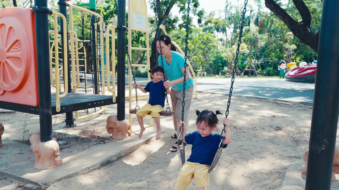 母亲和孩子们在操场秋千上嬉戏视频素材