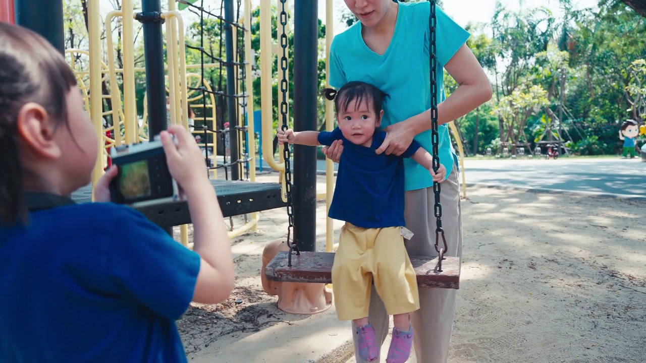 母亲和孩子们在操场秋千上嬉戏视频素材