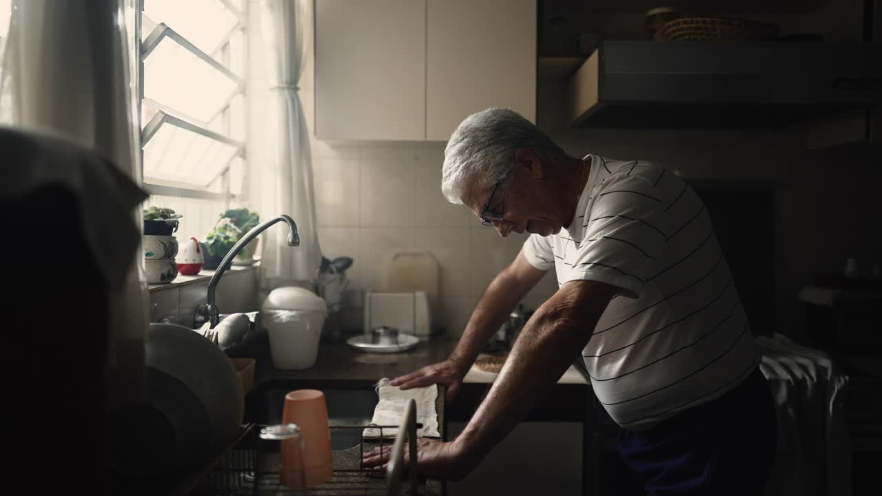 苦苦挣扎的老人靠在厨房柜台上，心事重重，抬头望向窗户，感到焦虑视频素材