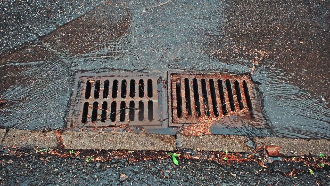 雨水顺着街道雨水下水道排水口流下视频素材