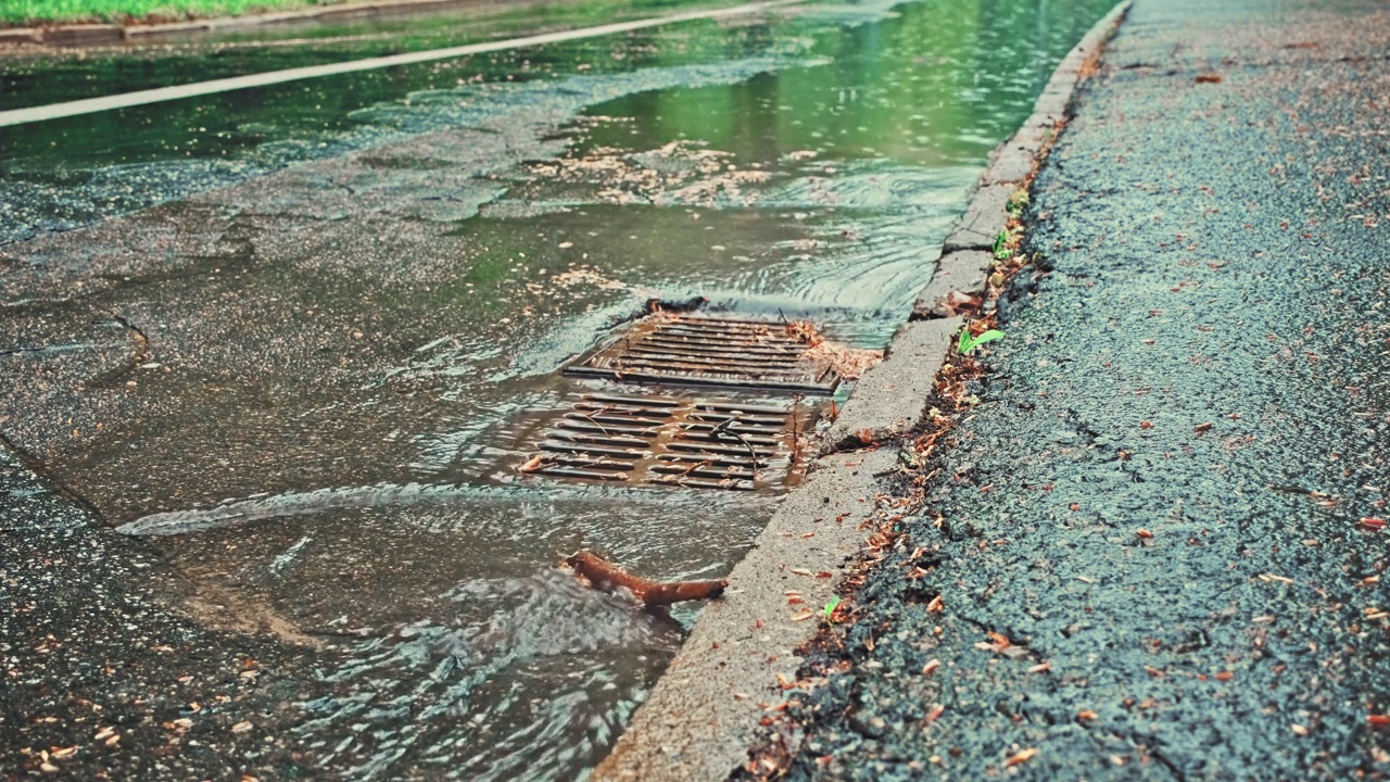 雨水顺着街道雨水下水道排水口流下视频素材