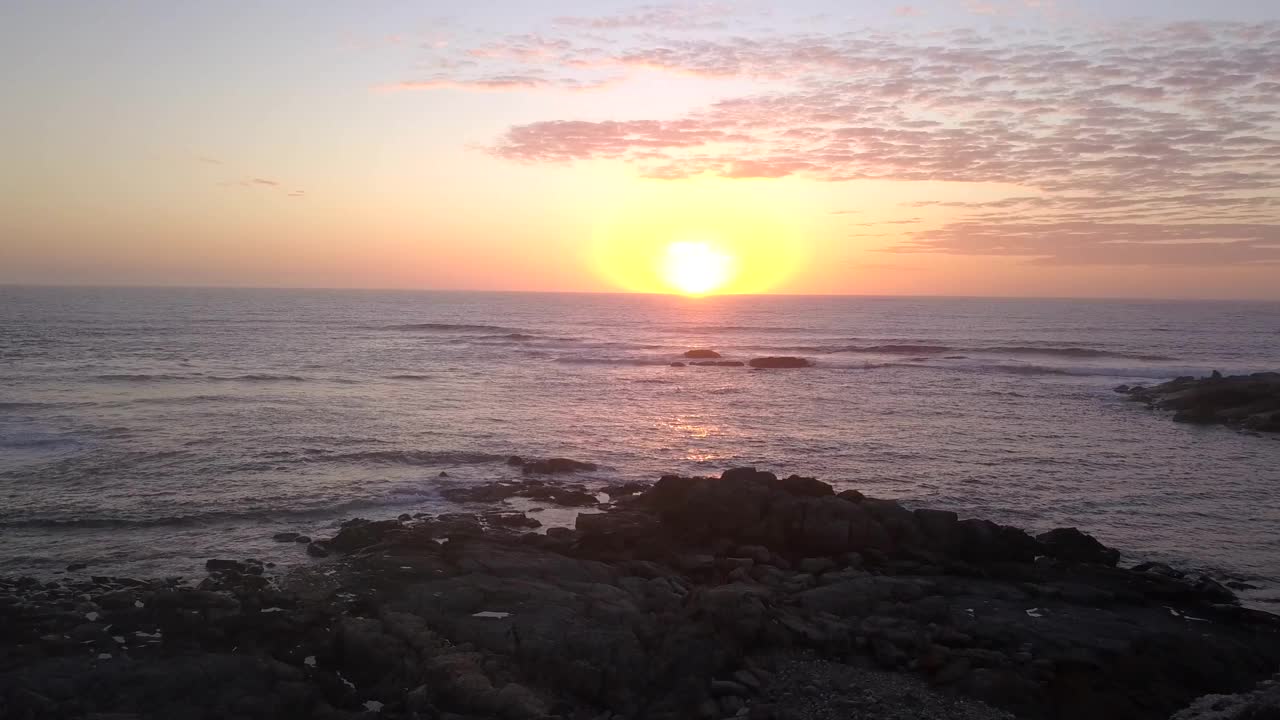 空中俯瞰土山，海滩，宁静的大海，地平线上橙色的日落天空视频素材