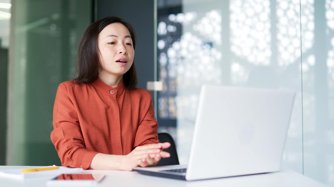 自信的亚洲女商人坐在办公室里用笔记本电脑进行视频通话视频素材