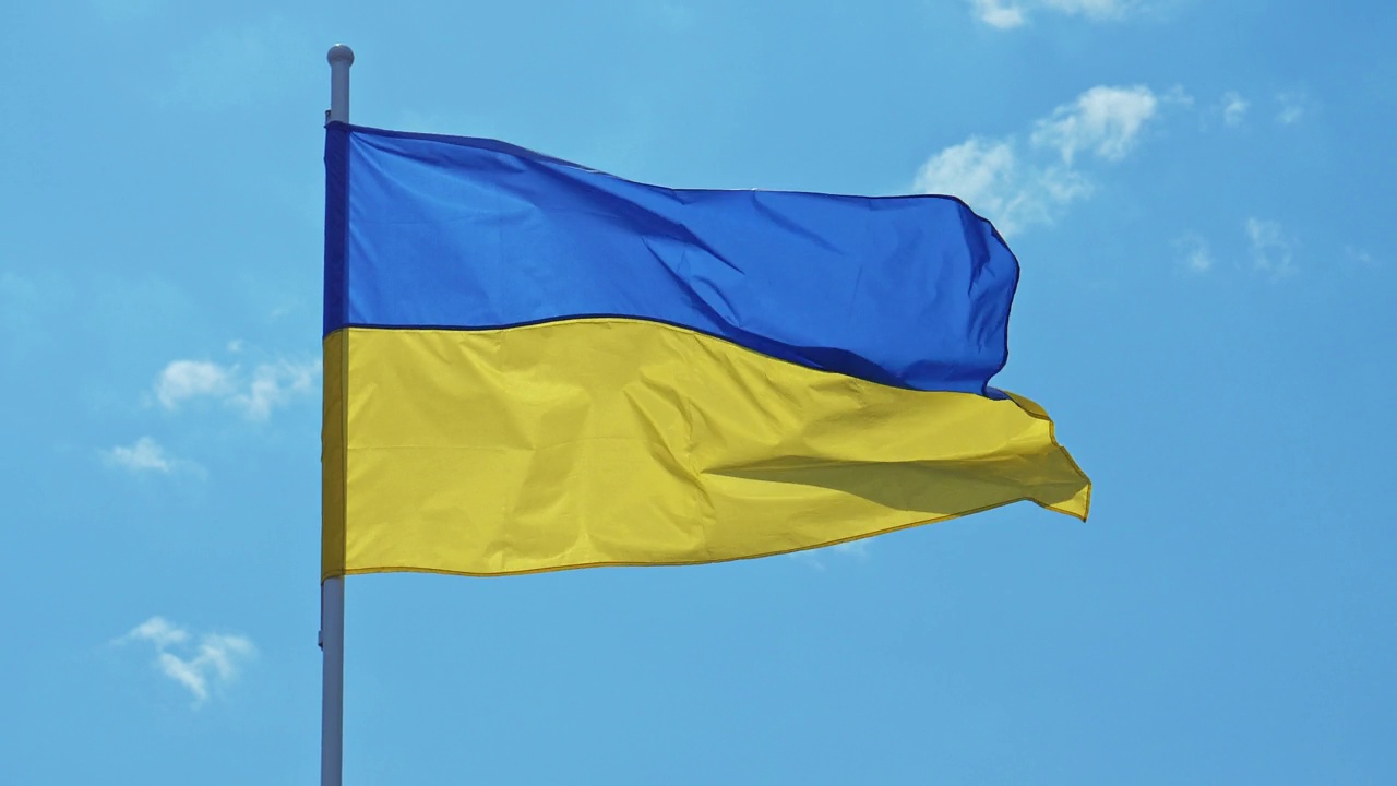 乌克兰国旗在蓝天背景上迎风飘扬。乌克兰的黄蓝色国旗在风中摇曳。乌克兰的民族象征。4 k的视频视频素材