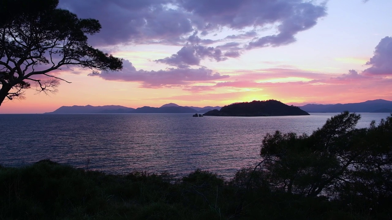 粉红色紫色的夕阳天空在海上和一系列的小山视频下载