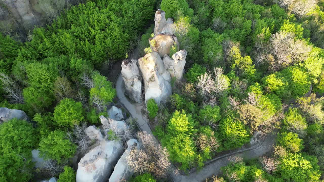 航拍视频，岩石山脉和明亮的绿色树木之间的道路视频素材