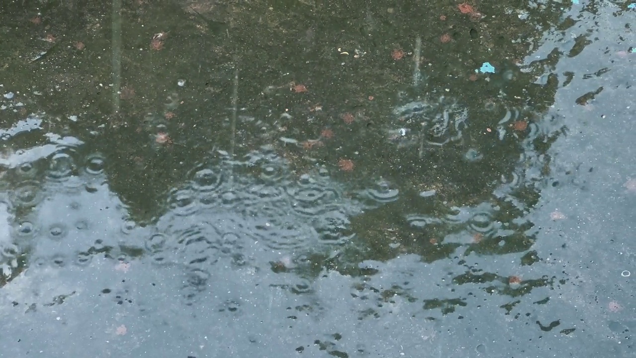 雨滴落在路上，水花向四面八方散开。视频素材