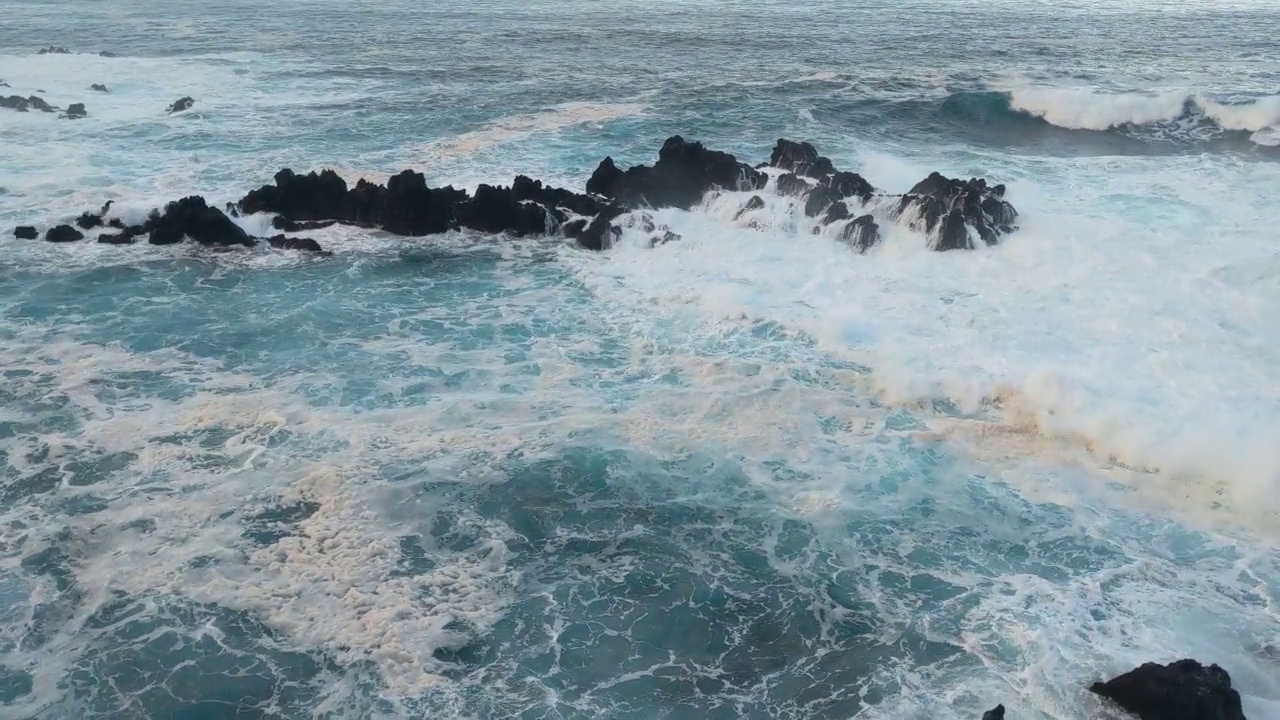 蓝色的海浪拍打着岩石。海浪撞击障碍物时产生的泡沫视频素材