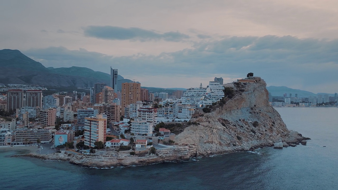 沿海城市，现代建筑坐落在岩石地形上，在金色的粉红色日落。夏日傍晚的现代海滨小镇。视频素材