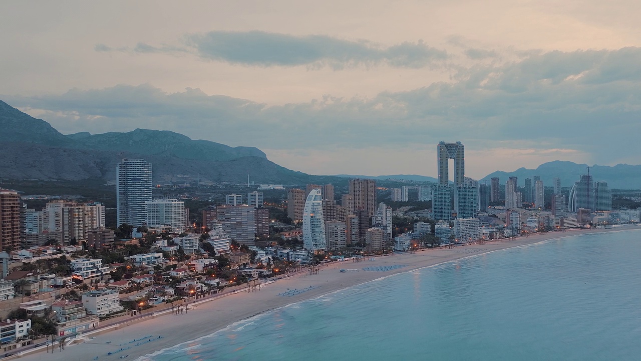 美丽的粉红色日落时分的海滨城市。现代建筑和摩天大楼紧挨着沙滩和海洋。视频素材