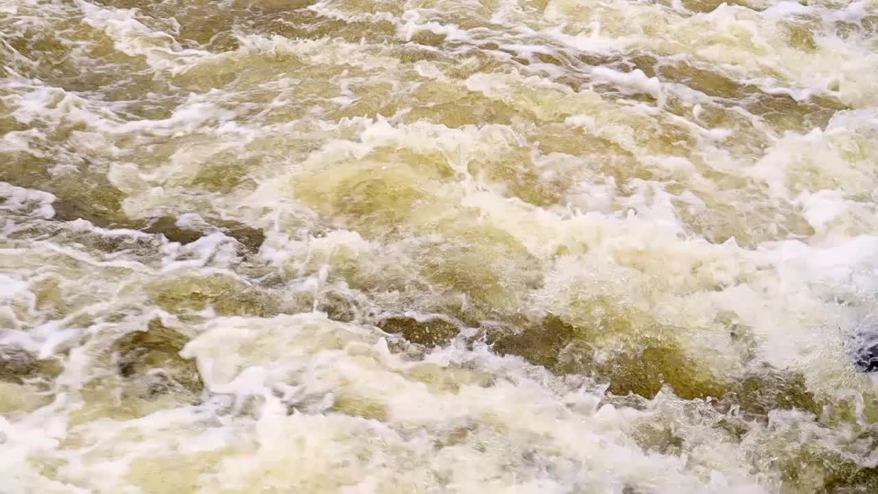 河急流。近距离抽象背景落水。水从河边的岩石上流过。一条美丽而有力的山河。河水湍急视频下载