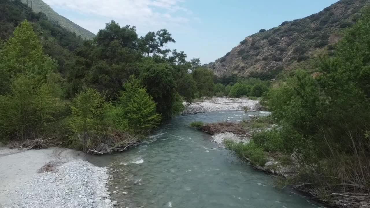 白天在绿树和山脉旁的河流航拍图视频素材