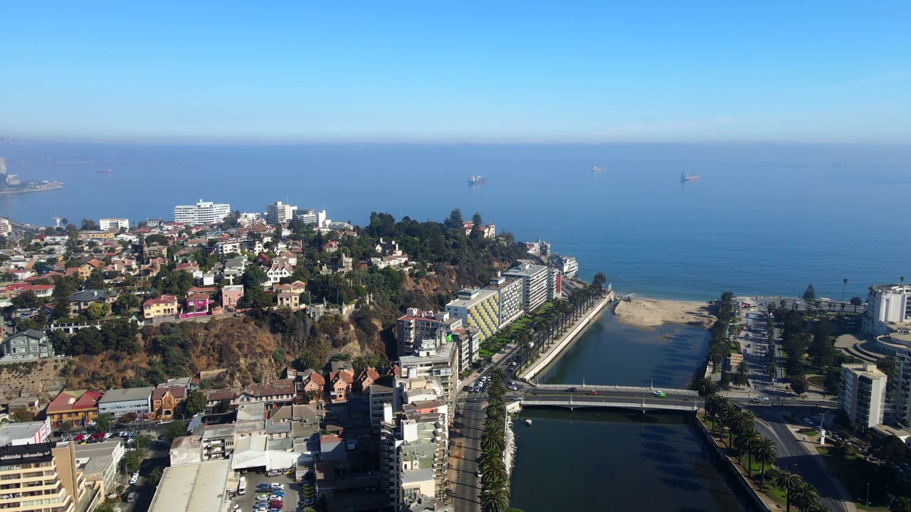 航拍无人机在沿海城镇上空盘旋，大桥横跨通往海湾的河流视频素材