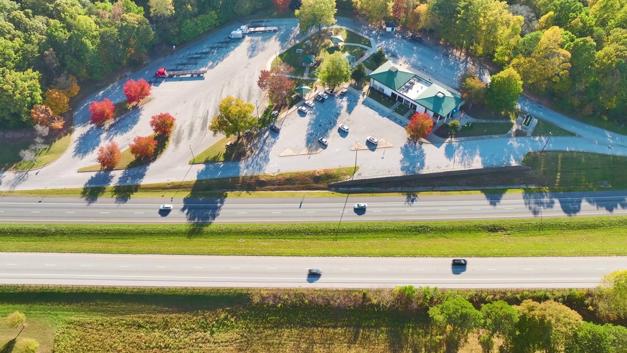 在繁忙的美国州际高速公路附近有休息区的大型卡车停靠站，有快速行驶的汽车和卡车。州际旅行期间的休闲停车场视频素材