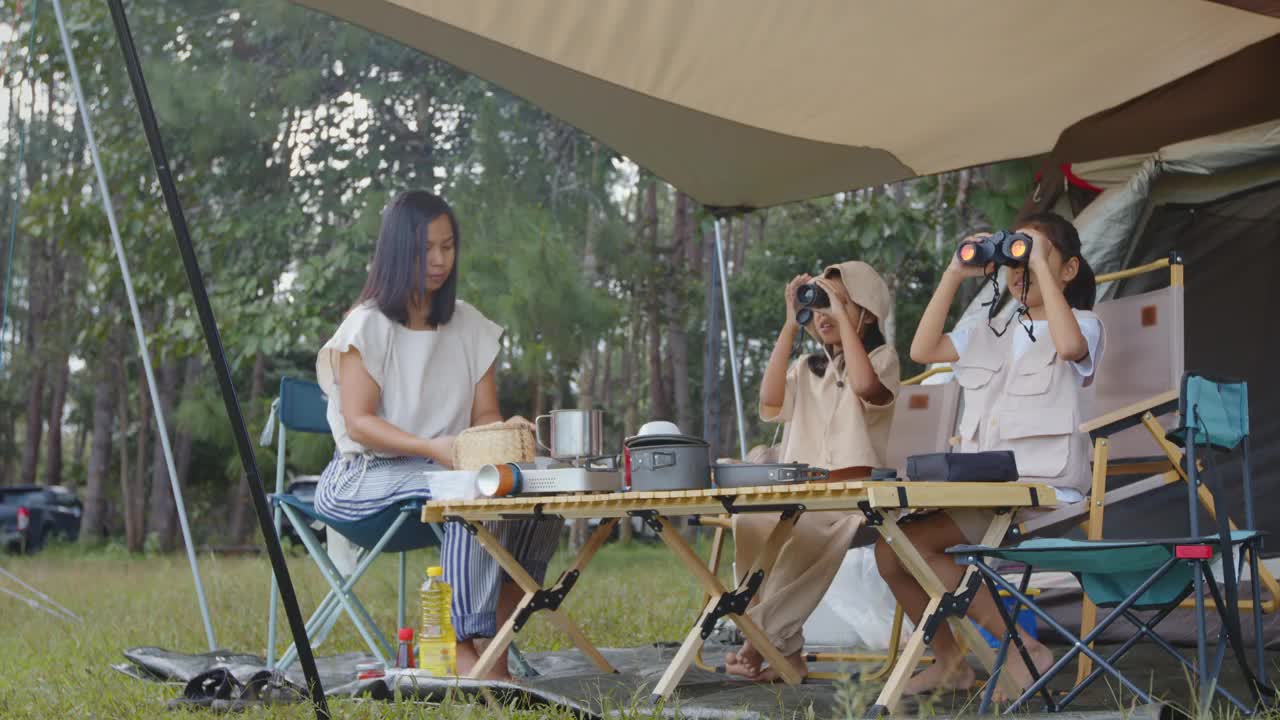 两个亚洲小女孩在营地用双筒望远镜观察视频素材