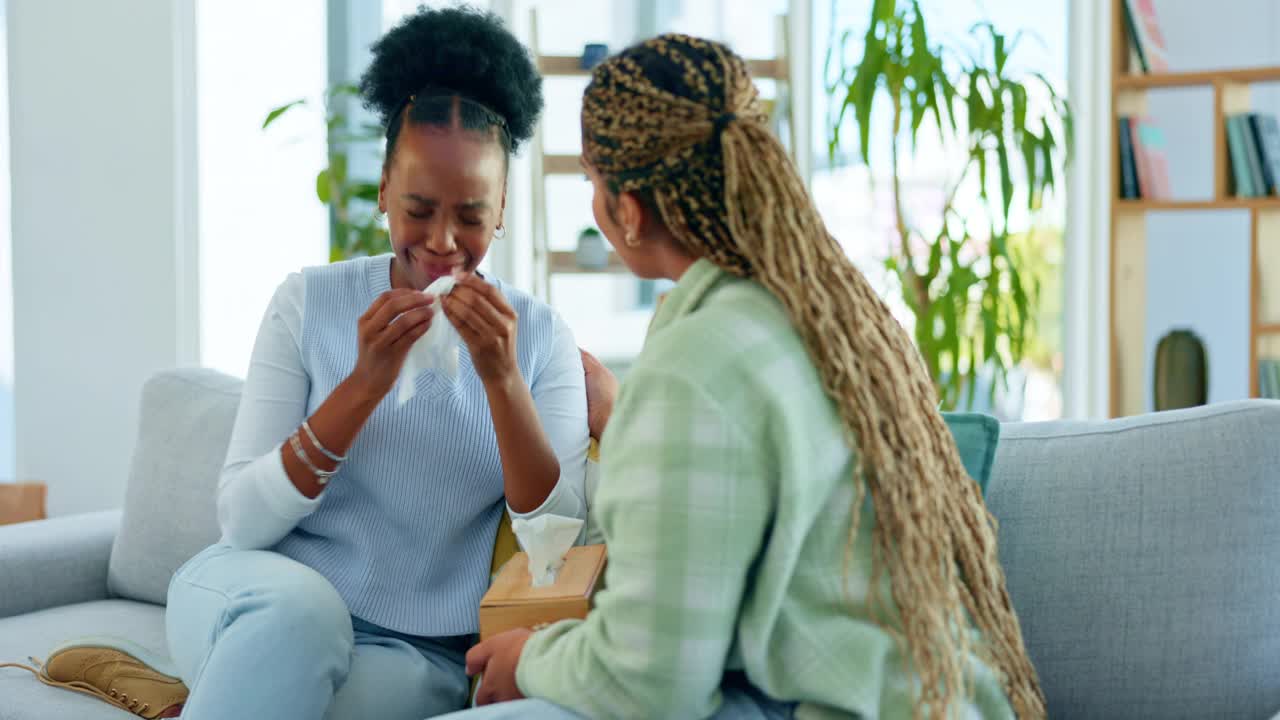 悲伤的黑人妇女，朋友和哭泣的人在沙发上支持，关心或理解一起在家里。非洲妇女与支持她的朋友在客厅沙发上哭泣，因为悲伤、情感或失去视频素材