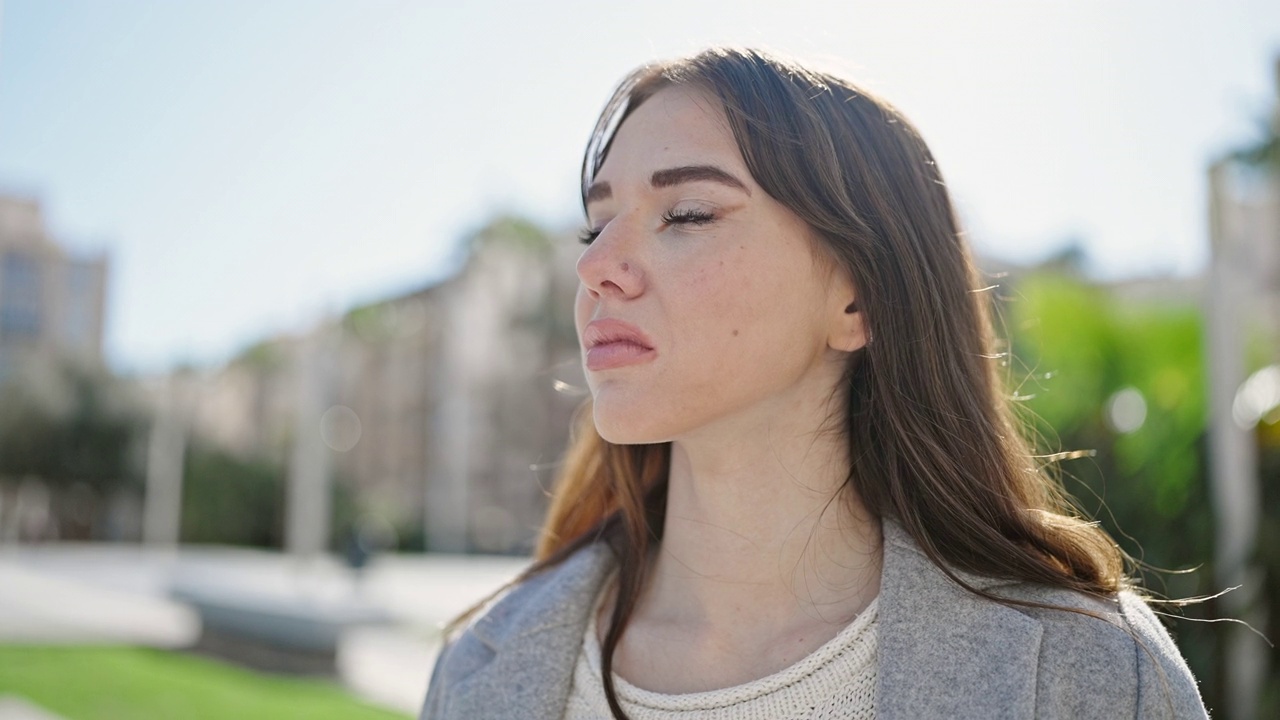 年轻的西班牙裔女子站在公园里，表情严肃地看着镜头视频素材