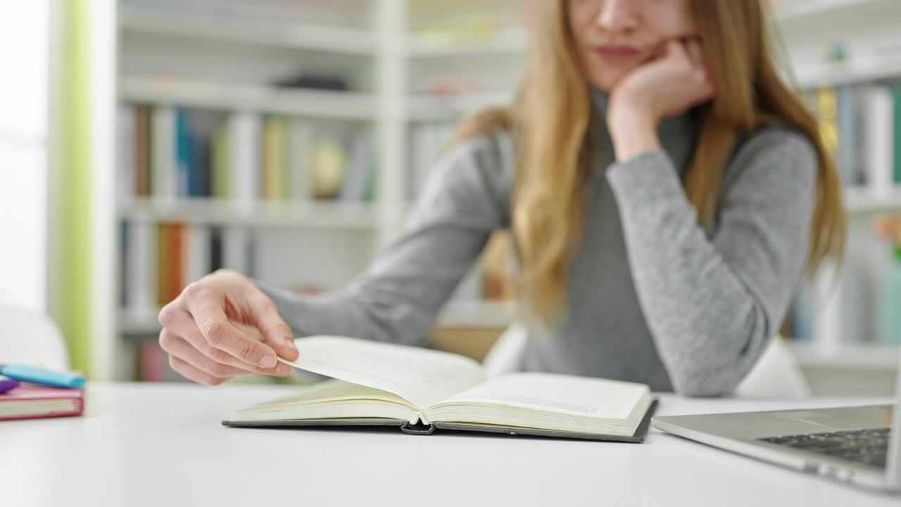 年轻的白人妇女坐在图书馆大学的桌子上看书视频素材