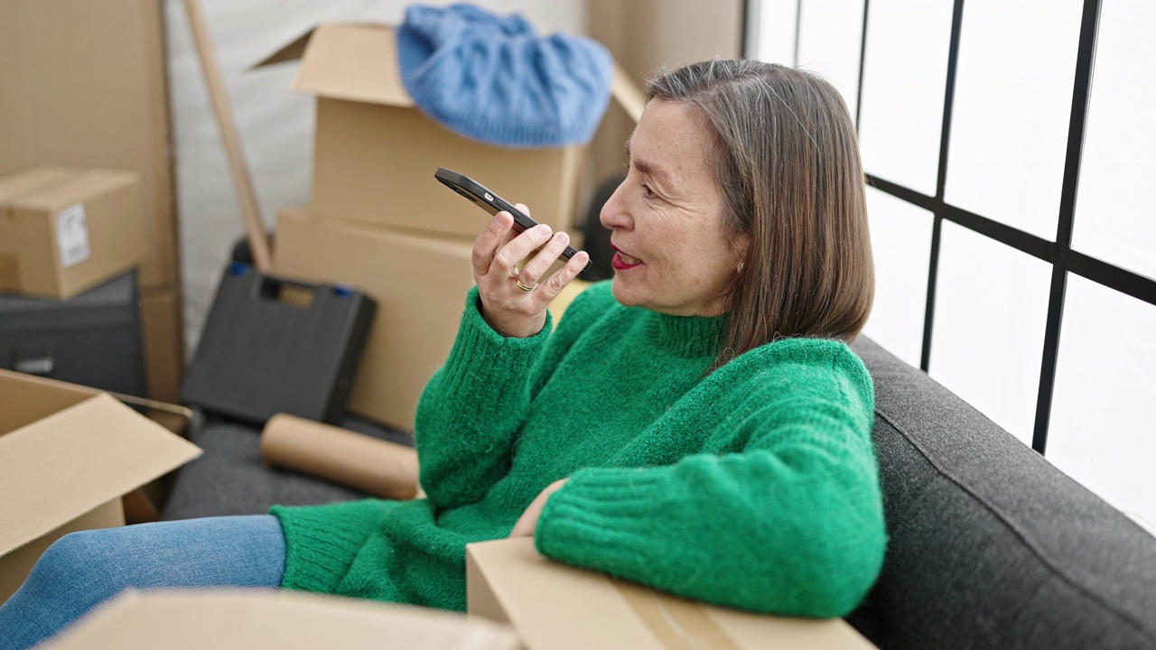 白发苍苍的成熟西班牙女人在新家用智能手机发语音信息视频素材