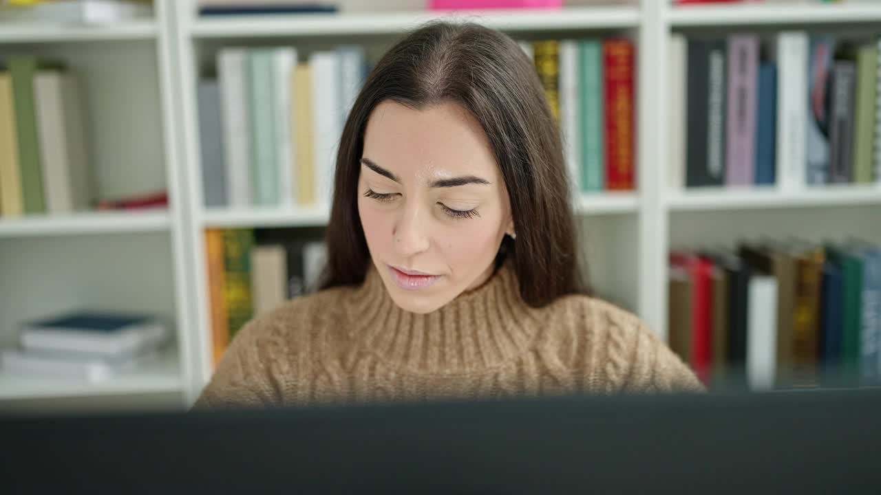 年轻漂亮的西班牙女学生在大学教室里用严肃的表情使用电脑视频素材