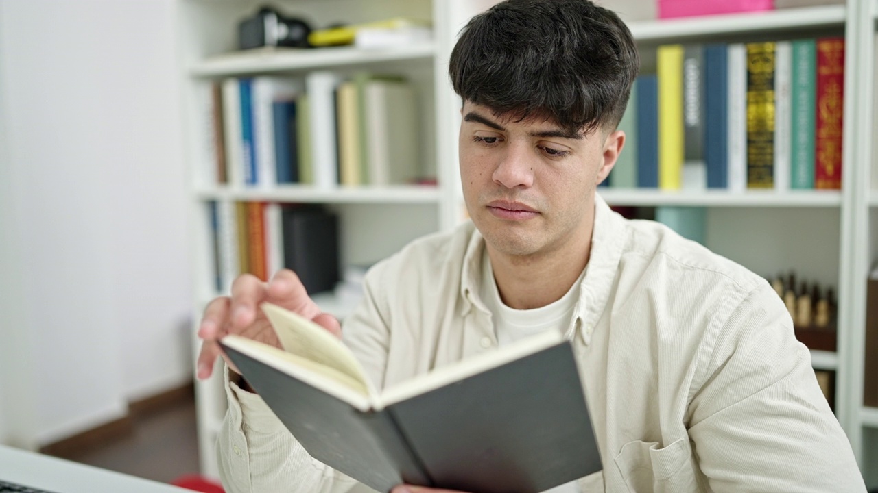 年轻的西班牙裔学生坐在图书馆大学的桌子上看书视频素材