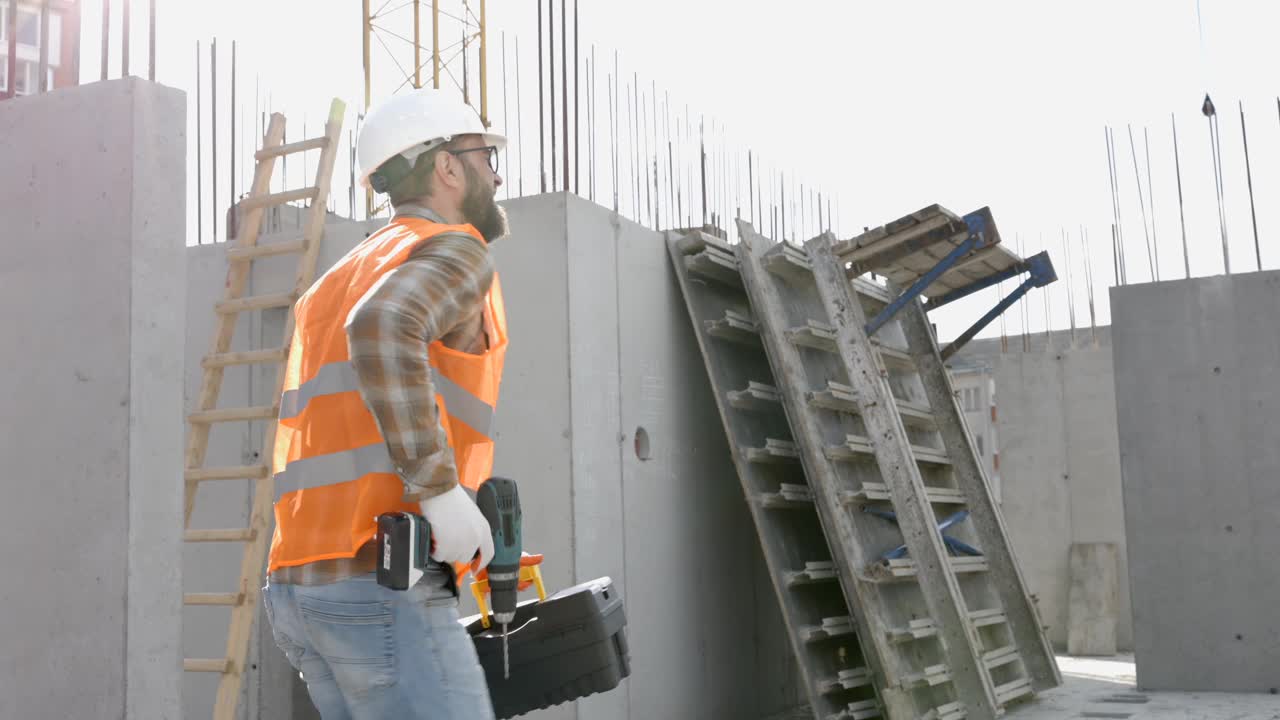 滑稽的建筑工人跳舞。戴着头盔的建筑工人的积极舞蹈。穿着建筑工人制服的建筑工程师在他的工作场所跳舞视频素材