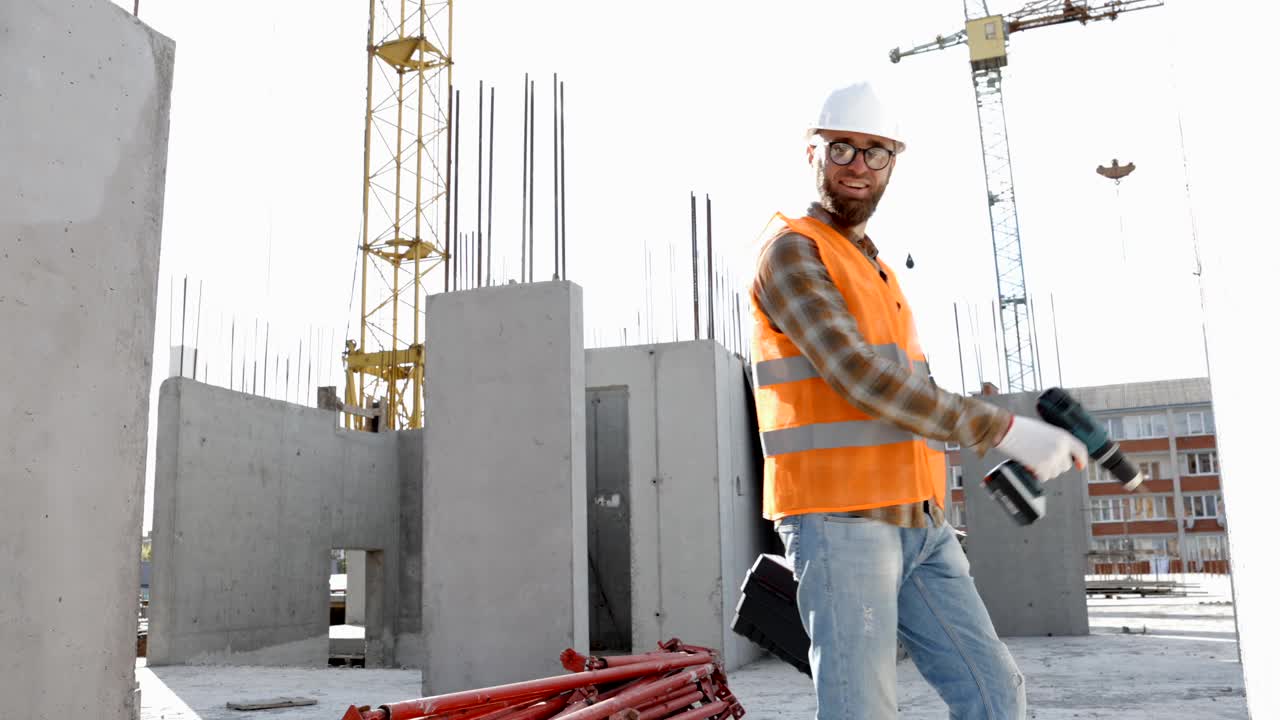 滑稽的建筑工人跳舞。戴着头盔的建筑工人的积极舞蹈。穿着建筑工人制服的建筑工程师在他的工作场所跳舞视频素材