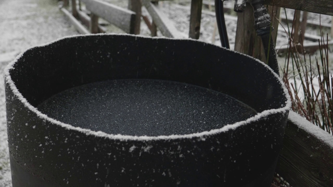 花园里，雪慢慢地落进一个结冰的桶里视频素材