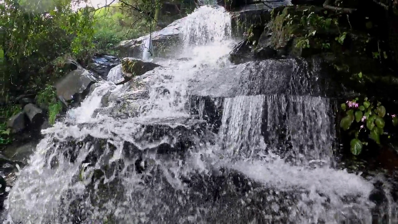 一种小瀑布，水流平滑地从岩石和石头上倾泻而下视频素材