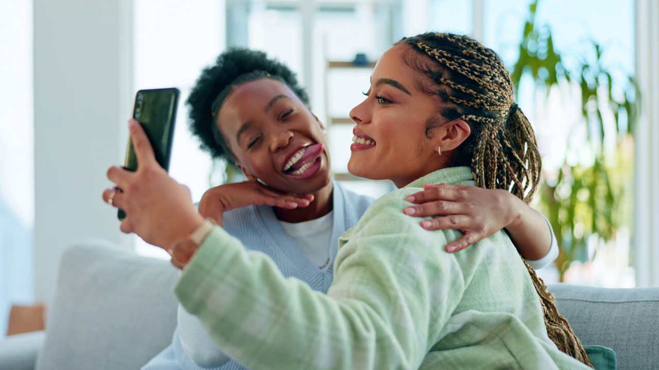 自拍、朋友和拿着手机的黑人女性，表情滑稽、滑稽、快乐，发布在社交媒体上。表情符号、网红和女孩们微笑着用智能手机记忆、个人资料照片和沙发上的视频博客视频素材