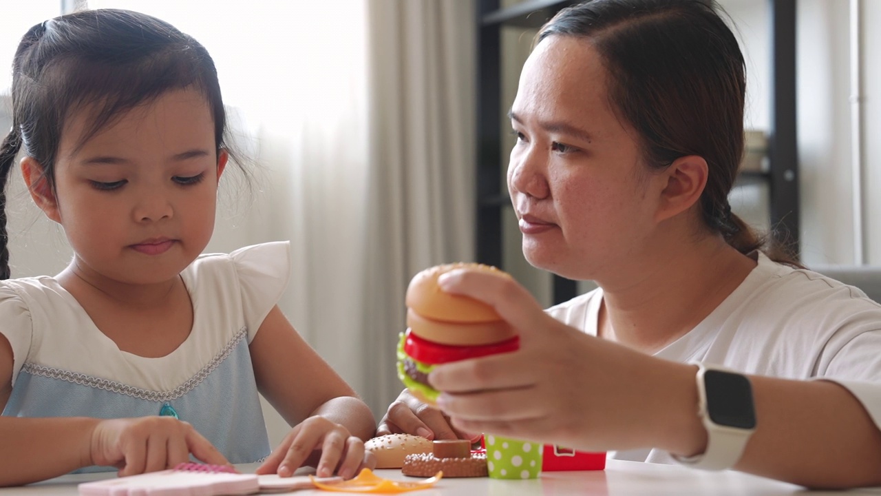 在想象中，妈妈和小女孩一起玩塑料儿童玩具视频素材