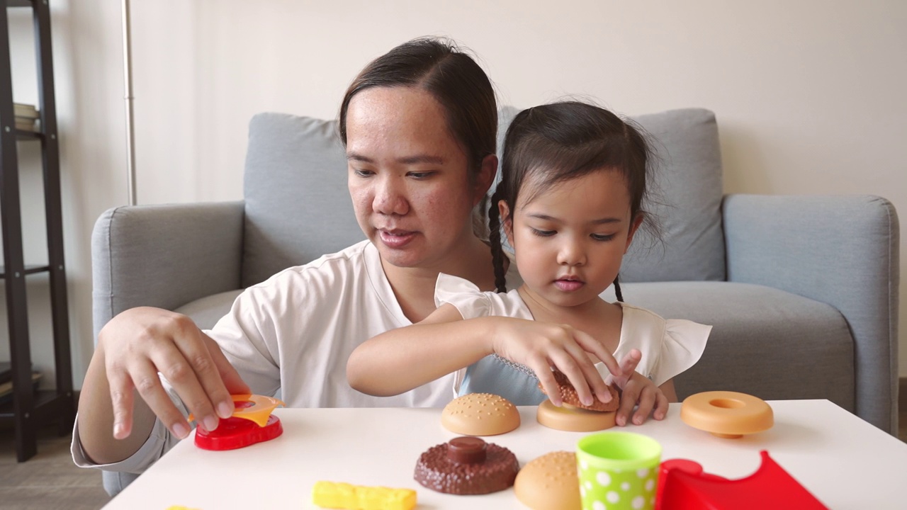 一个顽皮的亚洲妈妈和一个小女孩玩塑料儿童玩具视频素材