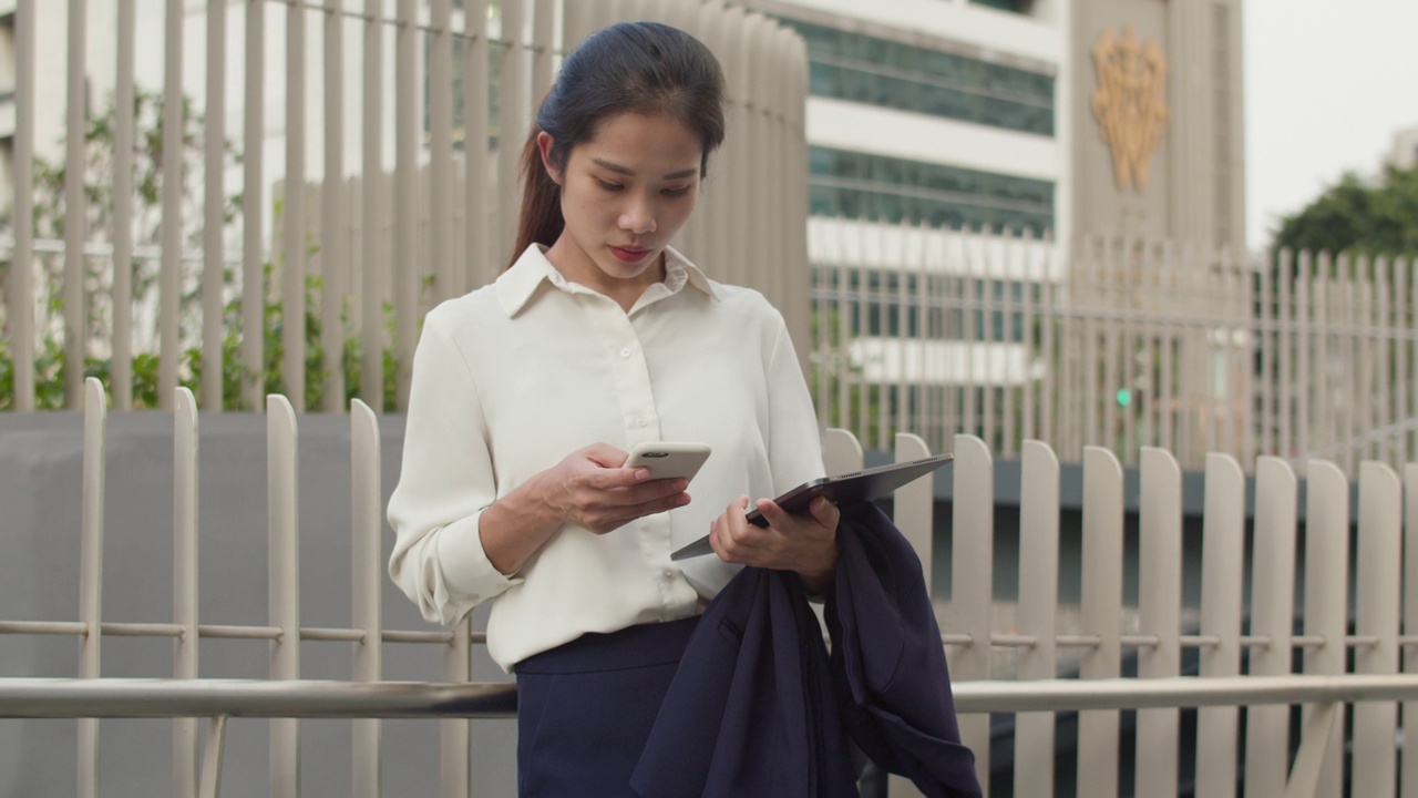 站在城市街道上使用智能手机的女商人。视频素材