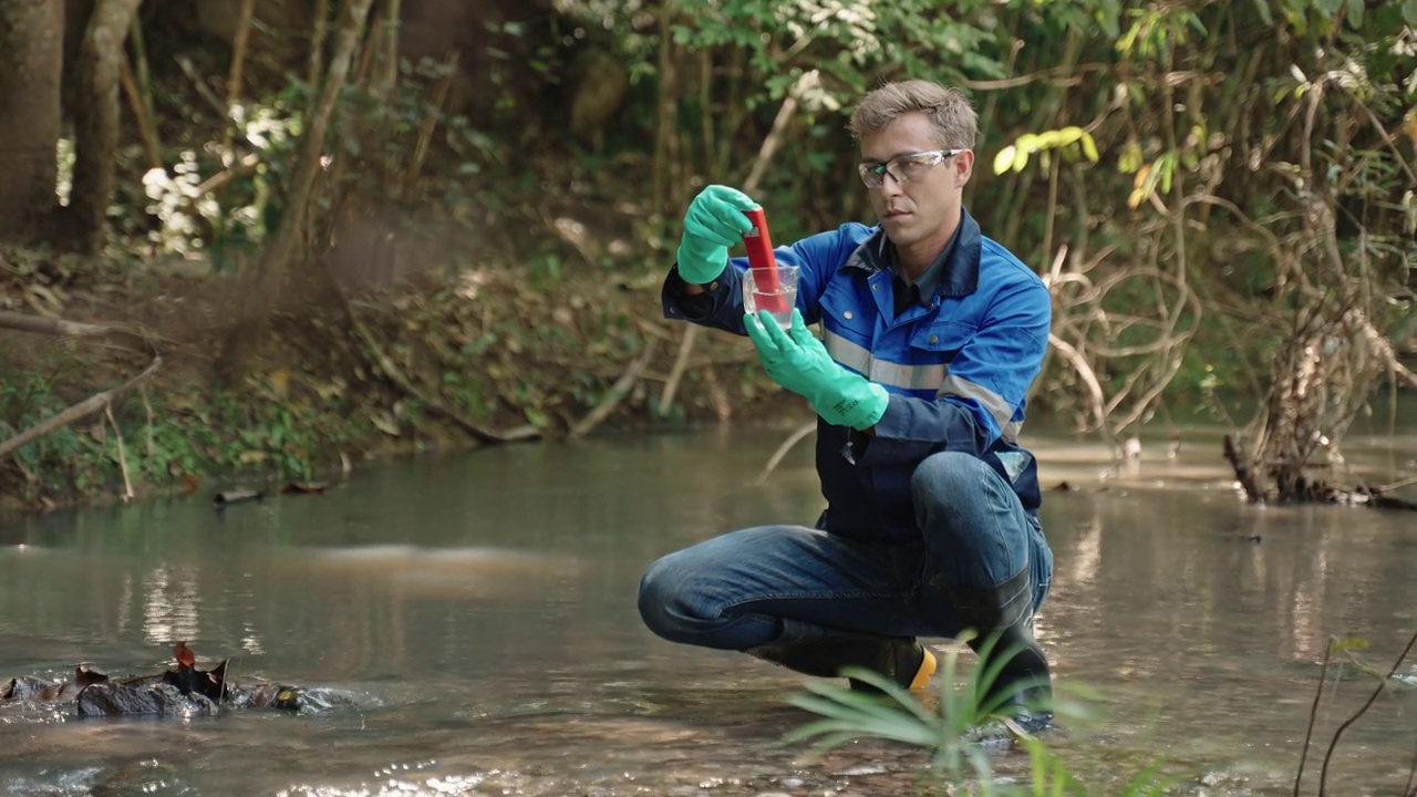 两名男性生物学家在当地的一条河里测试水。生态学家们穿着休闲服，在湖上探险，取水样。视频下载