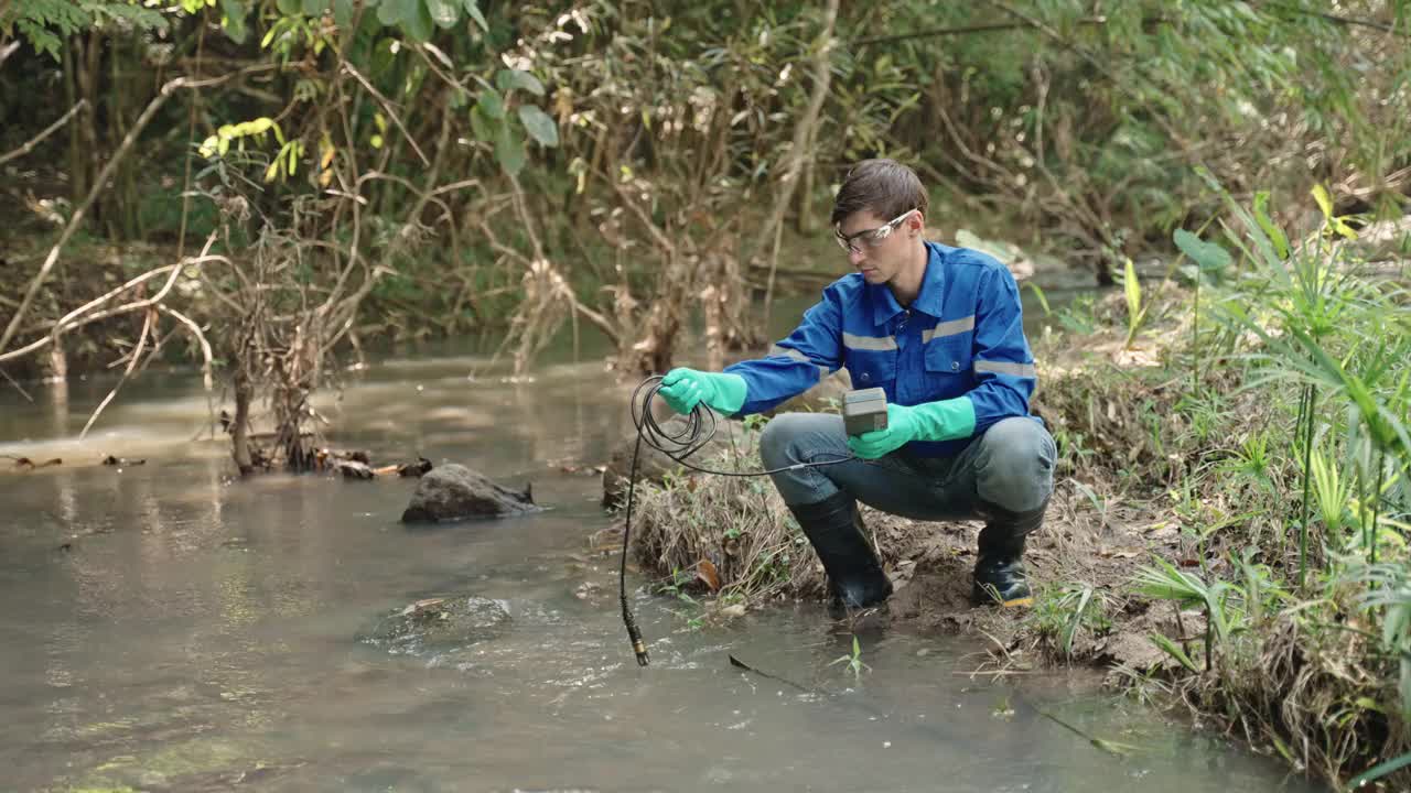 两名男性生物学家在当地的一条河里测试水。生态学家们穿着休闲服，在湖上探险，取水样。视频下载