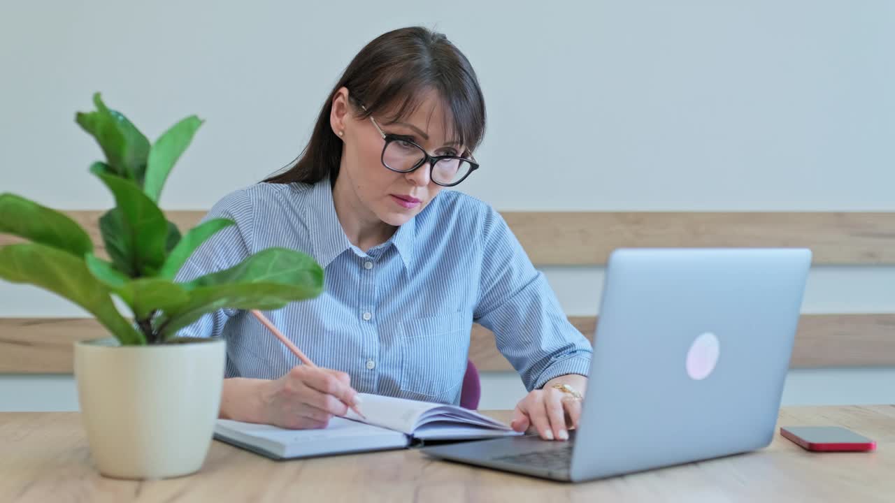 中年女商人用笔记本电脑，做笔记视频素材