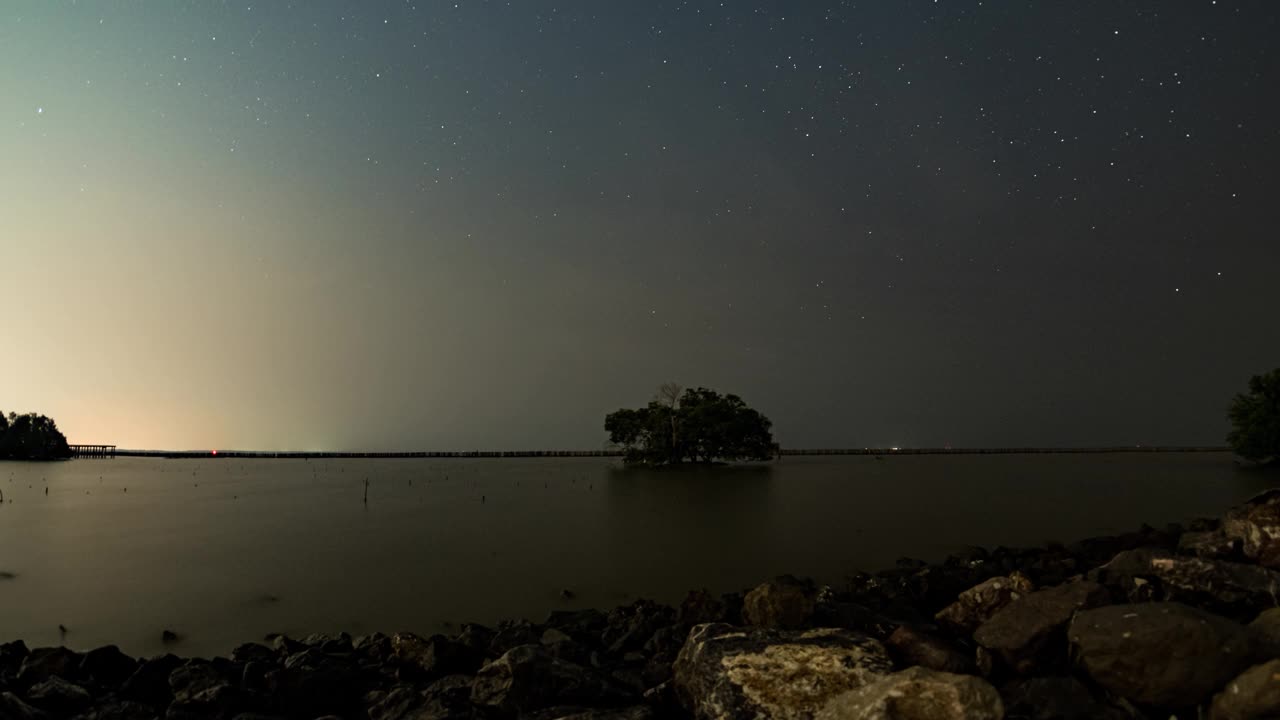 延时拍摄的银河在大海中央的一棵树上，泰国沙末沙空的马哈猜湾视频下载