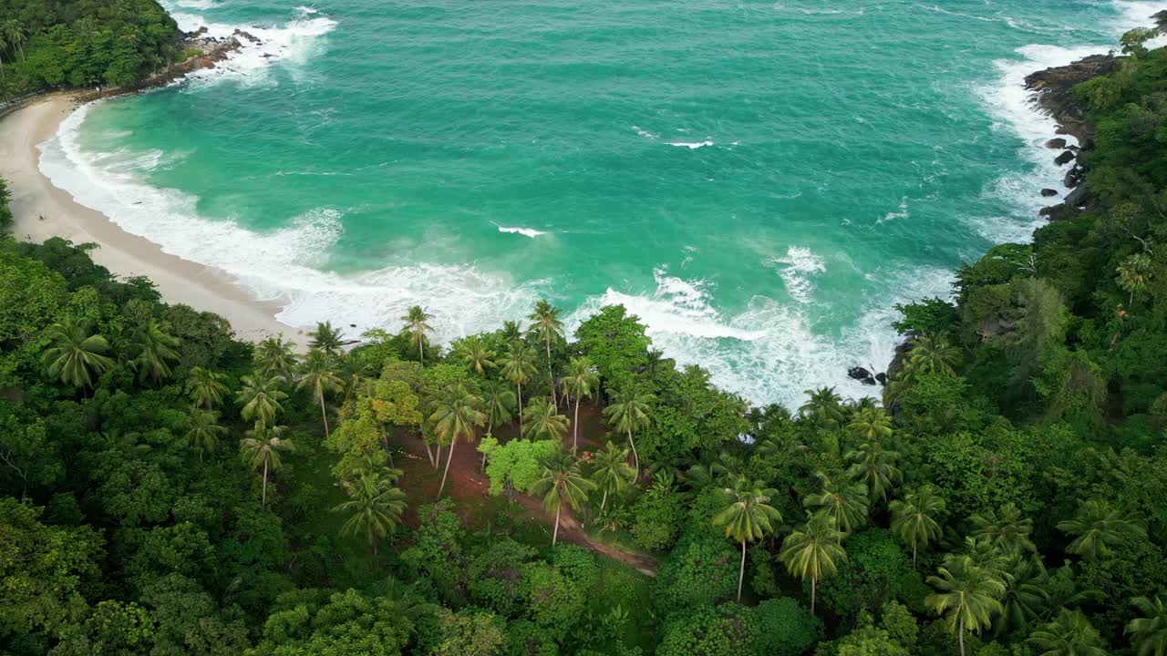 海滩鸟瞰图椰子树和巨大的海浪造成的强风造成的巨浪冲刷在泰国普吉岛海岸线上的山丘。视频素材